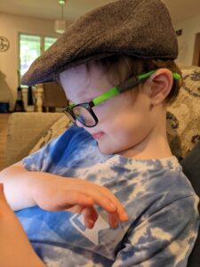 A boy reads while wearing reassembled spectacles without his cochlear processors being worn.